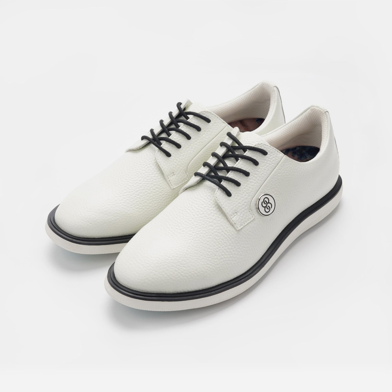 White sneakers with black laces and a sole on a light gray background sells at Paradise Golf