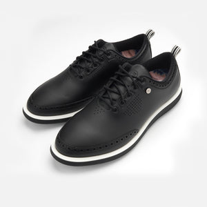 Pair of black leather shoes with white soles on a light gray background sells at Paradise Golf