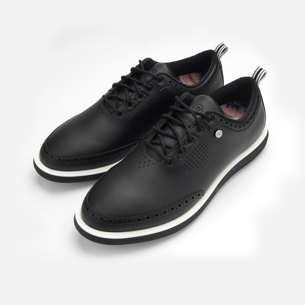 Pair of black leather shoes with white soles on a light gray background sells at Paradise Golf