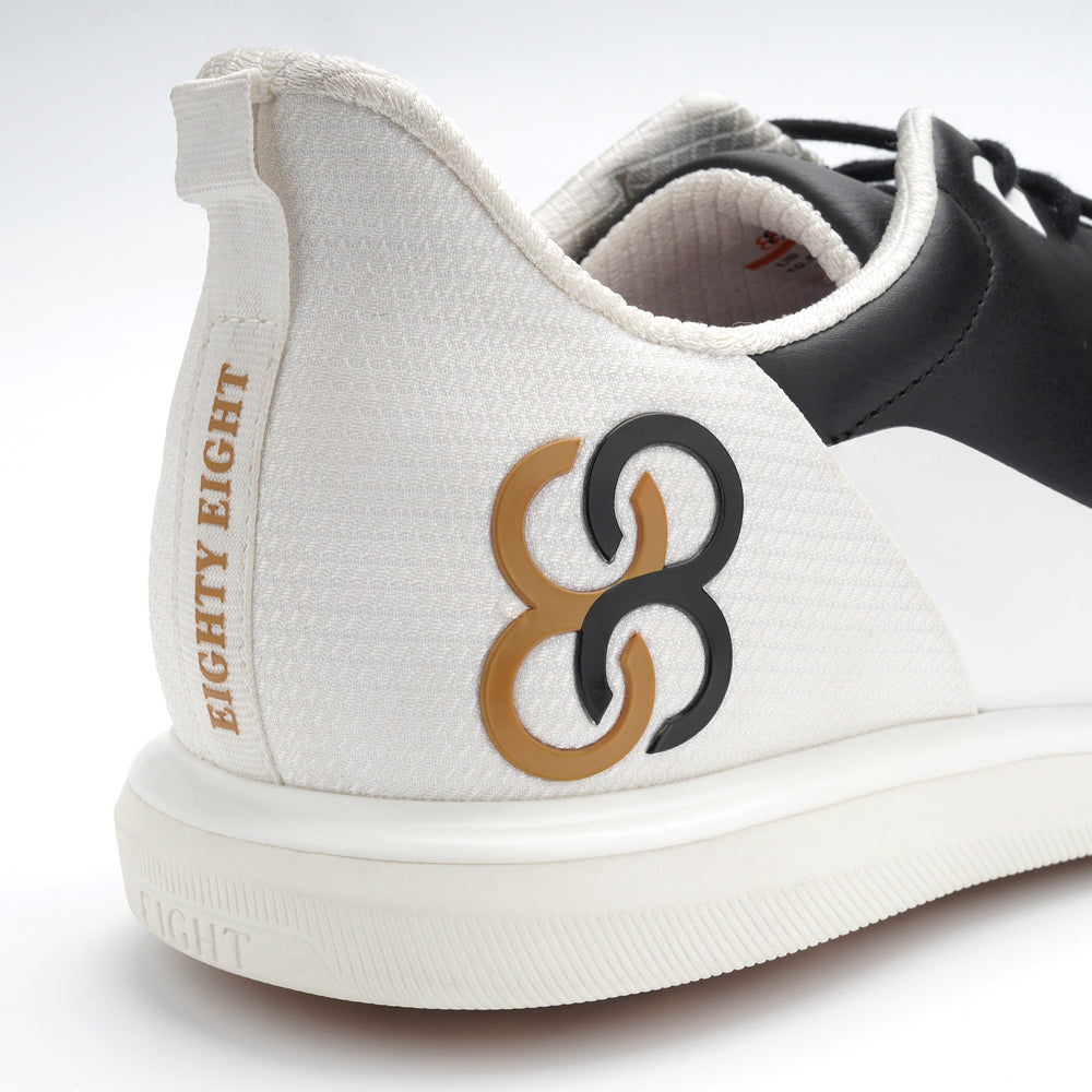 White sneaker with black and gold logo on a white background sells at Paradise Golf
