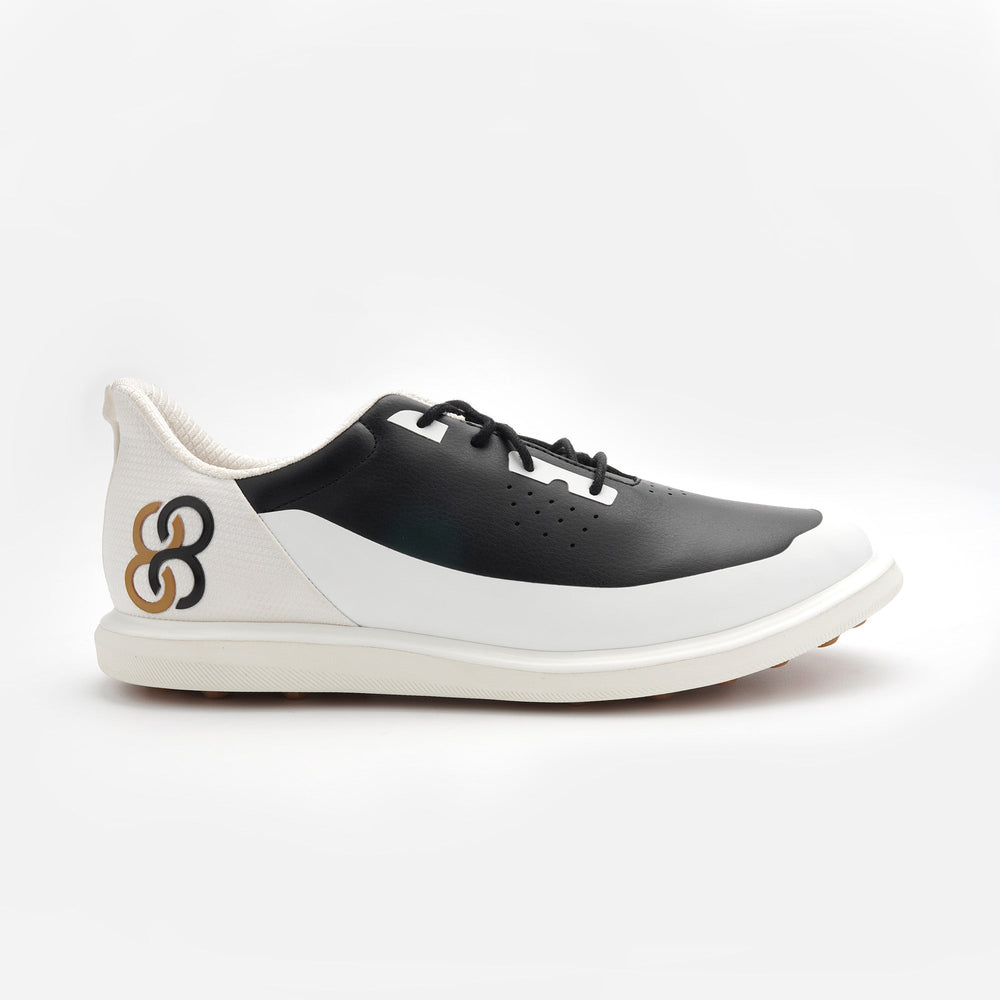 Black and white sneaker with a brand logo on a light gray background sells at Paradise Golf