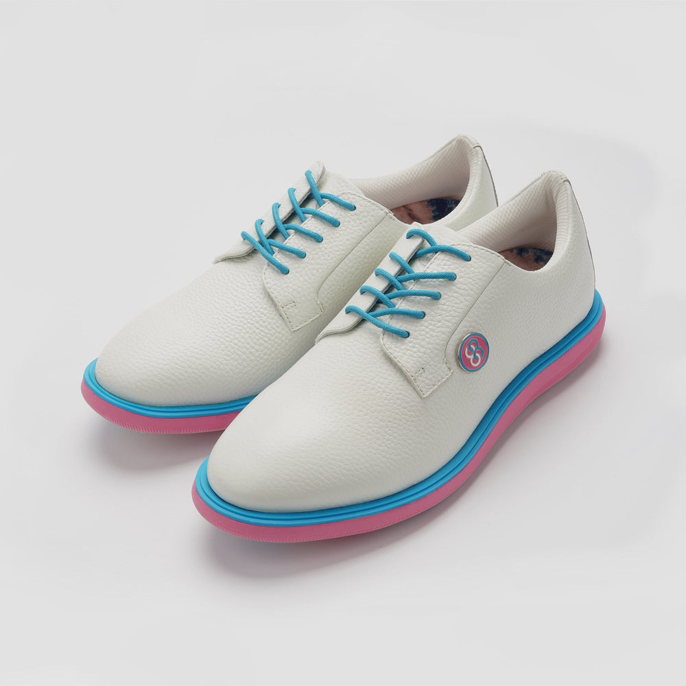 White shoes with blue laces and pink soles on a light gray background sells at Paradise Golf
