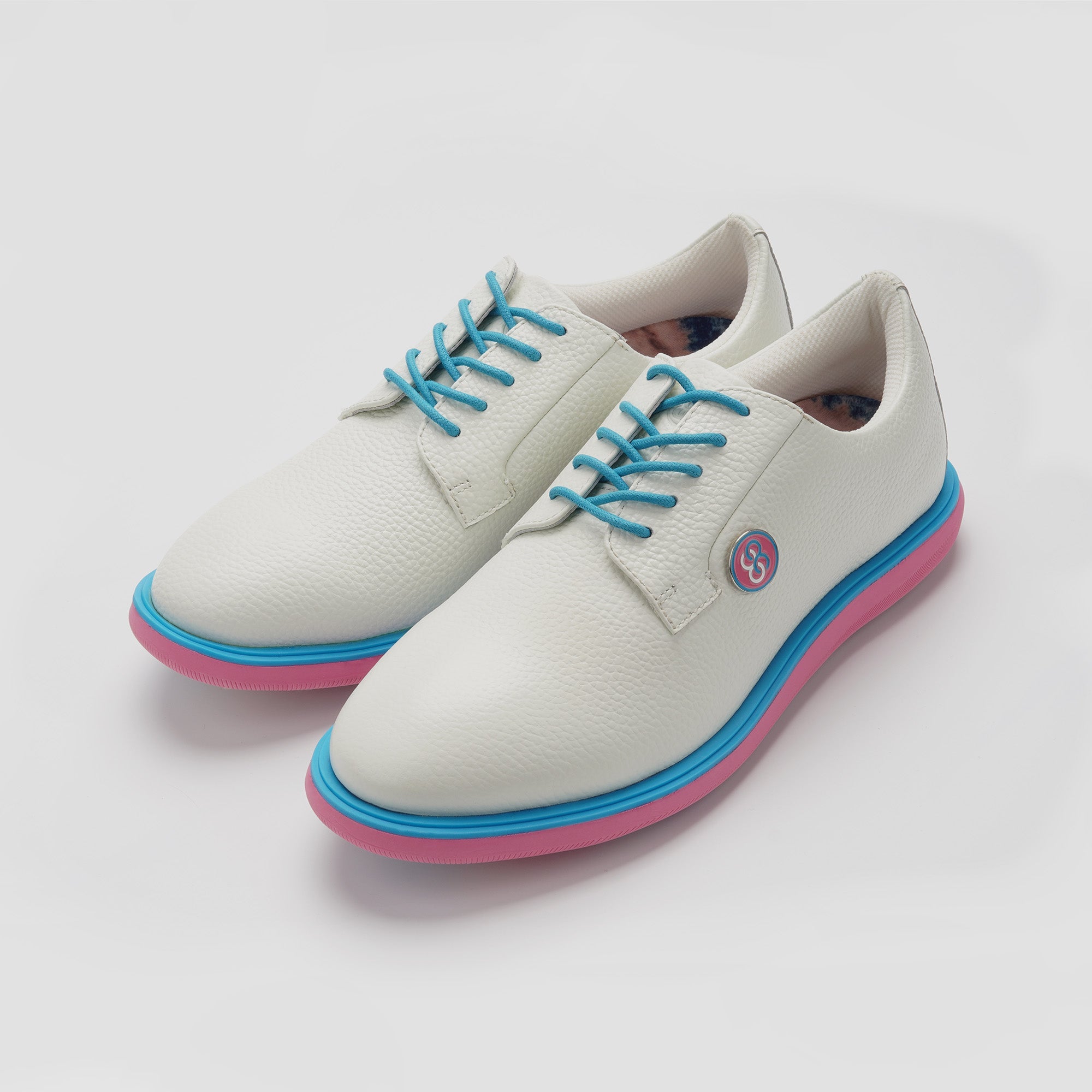 White shoes with blue laces and pink soles on a light gray background sells at Paradise Golf