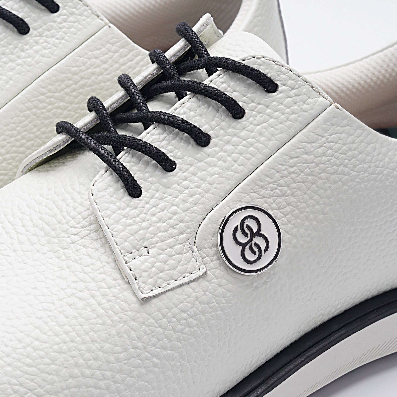 White shoe with black laces and a logo on a white background sells at Paradise Golf