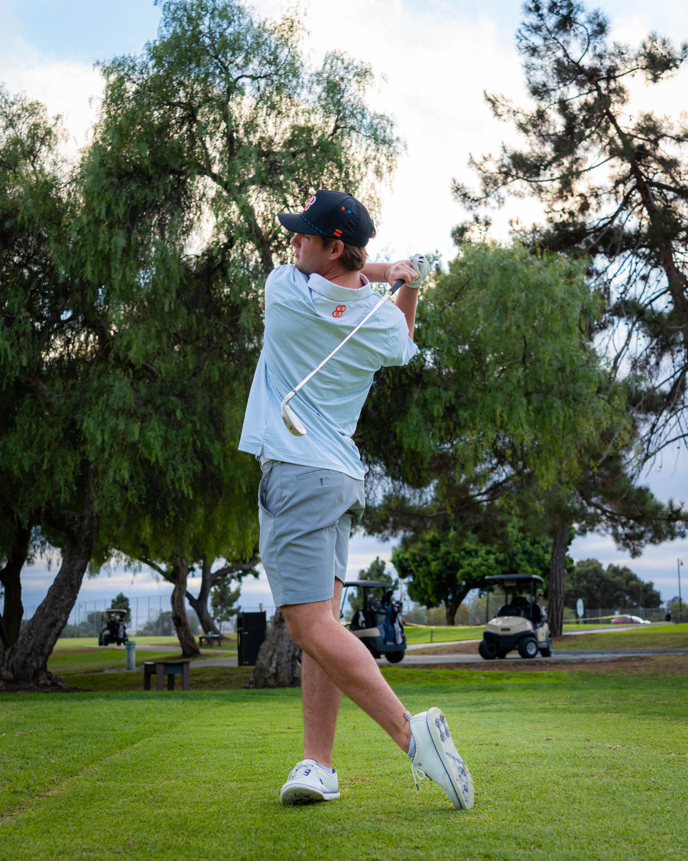 Person playing golf on a green course with trees in the background sells at Paradise Golf